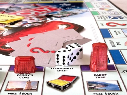 图片展示的是《大富翁》游戏棋盘的一部分。棋盘上有“Peggy's Cove”“Community Chest”“Cabot Trail”等地点,以及“Luxury Tax”“Chance”等特殊区域。棋盘上摆放着红色的房屋模型、白色 自动生成
